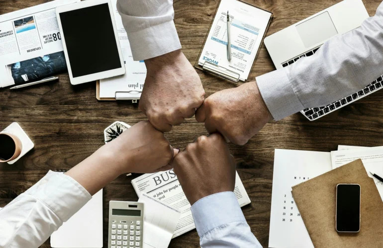 Equipo uniendo los puños sobre una mesa de trabajo
